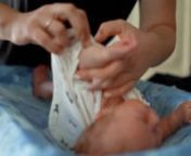A mother changes her baby&#39;s shirt and diaper.