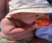 Cute baby eating apple from young breastfeeding g mom