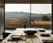 Prompt Midjourney : focus on a winery&#39;s set table, ultra modern style like Antinori Winery, with element of nature like rough wood table and element of cement and rough material. ultra light and neutral with remember of wine, out of a large metal window all the vineyards